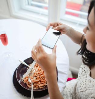 Jeune femme photographiant son assiette