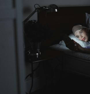 Femme dans son lit avec son téléphone